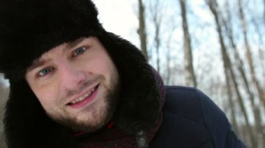 Karlı bir sokakta, kış şapkalı komik bir adamın portresi kameraya bakıyor.