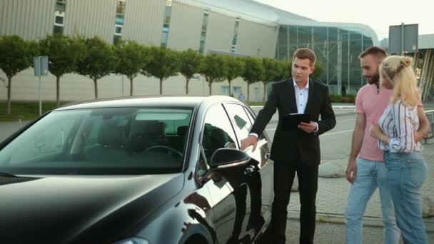Πωλητής πωλήσεων σύμβουλος με φάκελο στο χέρι σε κοστούμι πωλεί το αυτοκίνητο. Αγορά — Αρχείο Βίντεο