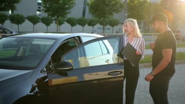 Mujer con camisa a rayas. Vendedor entrega lanzamiento de ventas al hombre comprando vehículo. — Vídeos de Stock