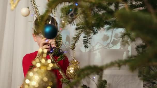 Um rapaz a espreitar de um abeto. Rapaz alegre escondido atrás da árvore de Natal. — Vídeo de Stock