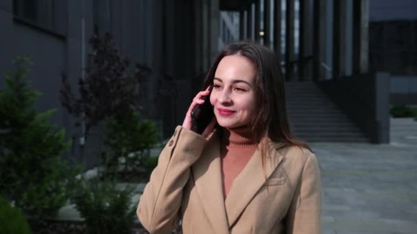 Жінка розмовляє телефоном зовні в американському стилі Бізнес-центр на фоні — стокове відео