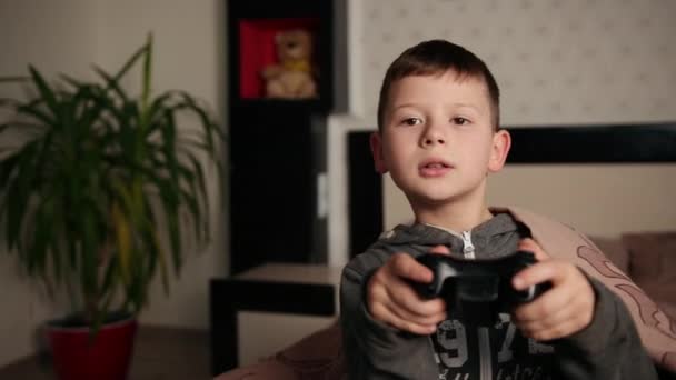 Le gars joue sur la console, le petit garçon joue au jeu vidéo assis sur le canapé — Video