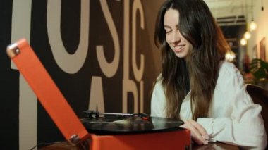 Evde eski pikabı ve vinil diskleri olan genç bir kadın. Kadın vinil sesi