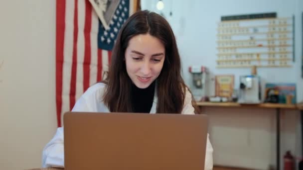 Frau arbeitet am Computer im Hintergrund hängt eine amerikanische Flagge. — Stockvideo