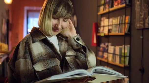 Προσωπογραφία έξυπνου φοιτητή με ανοιχτό βιβλίο που το διαβάζει στη βιβλιοθήκη του κολεγίου. Γυναίκα — Αρχείο Βίντεο