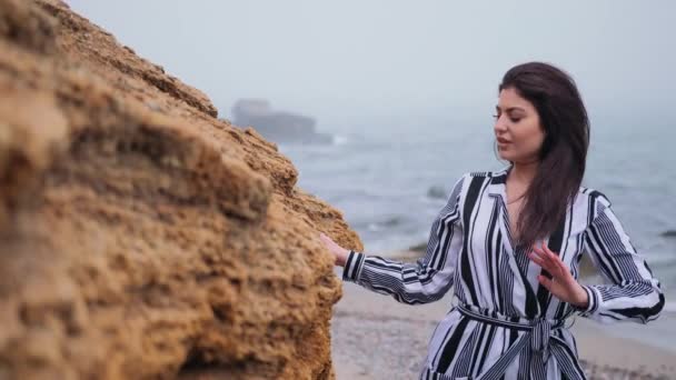 Freiberuflich. Mädchen steht mit wehendem Haar in der Nähe einer Klippe mit Blick auf den Ozean. — Stockvideo