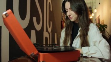 Evde eski pikabı ve vinil diskleri olan genç bir kadın. Kadın vinil sesi