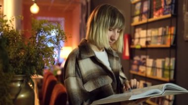 Üniversite kütüphanesinde açık kitap okuyan zeki bir öğrencinin portresi. Kadın.