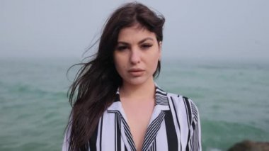 Denizde gülümseyen genç bir kadının portresi. Esmer kadın eğleniyor. Rüzgâr