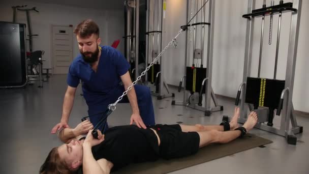 Sanierungskonzept. Junger Mann macht Übungen unter Physiotherapeut — Stockvideo