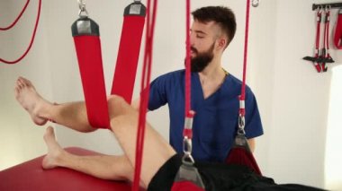 Genç adamın diz eklemi osteopatik manuel terapist tarafından manipüle ediliyor..