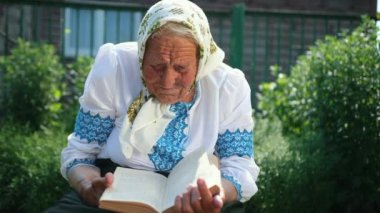 Yaşlı bir büyükanne sokakta oturuyor ve bir kitap okuyor. Vyshyvanka