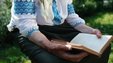 Yaşlı bir büyükanne sokakta oturuyor ve bir kitap okuyor. Vyshyvanka