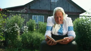 Yaşlı bir büyükanne sokakta oturuyor ve bir kitap okuyor. Vyshyvanka