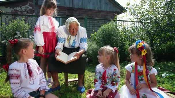 Una vecchia nonna è seduta per strada a leggere un libro. Vyshyvanka. — Video Stock