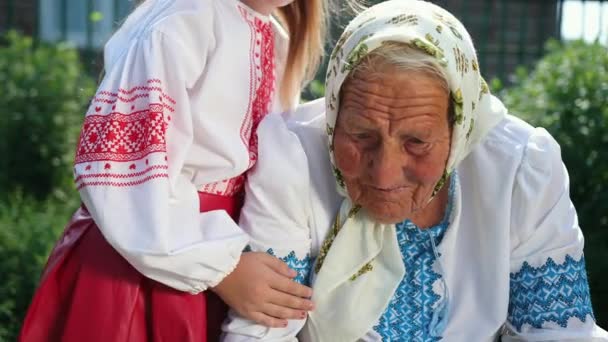 An old grandmother is sitting on the street and reading a book. Vyshyvanka. — Stock Video