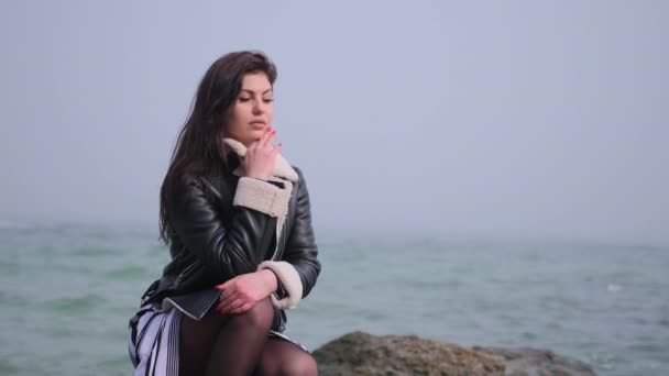 Fiatal nő sziklás tengerparton élvezi a kilátás nyílik a tengerre ősszel. Gyönyörű táj. — Stock videók