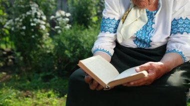 Yaşlı bir büyükanne sokakta oturuyor ve bir kitap okuyor. Vyshyvanka