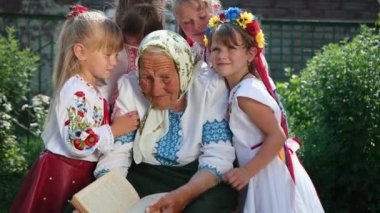 Yaşlı bir büyükanne sokakta oturuyor ve bir kitap okuyor. Vyshyvanka.