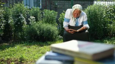 Yaşlı bir büyükanne sokakta oturuyor ve bir kitap okuyor. Vyshyvanka