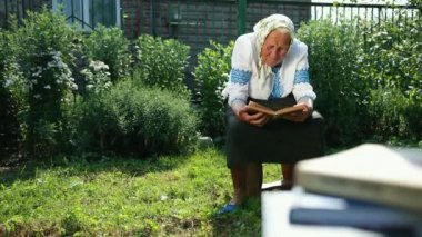 Yaşlı bir büyükanne sokakta oturuyor ve bir kitap okuyor. Vyshyvanka