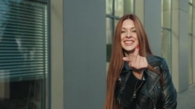 Siyah deri ceketli çekici ve çekici bir kadın etrafında dönüyor.