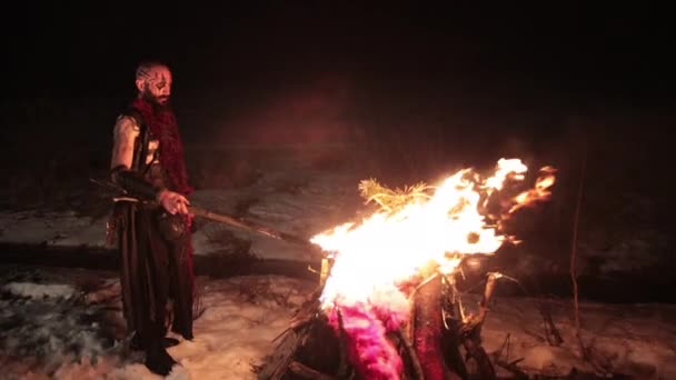 Вікінг з факелом запалює багаття. Жорстокий чоловік воїн небезпечної зовнішності біля вогню . — стокове відео