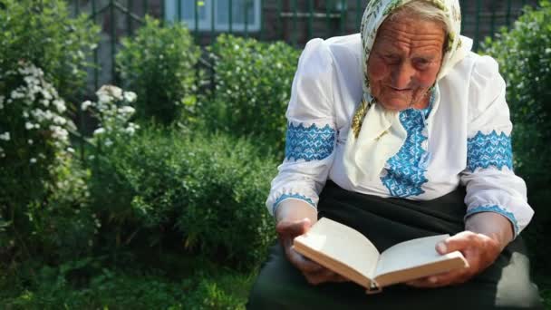 Seorang nenek tua duduk di jalan dan membaca buku. Vyshyvanka — Stok Video