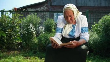 Yaşlı bir büyükanne sokakta oturuyor ve bir kitap okuyor. Vyshyvanka