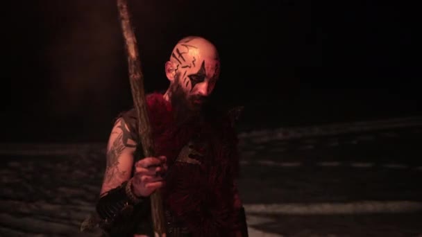 Vikingo con una antorcha enciende la hoguera. Brutal guerrero masculino de apariencia peligrosa por el fuego. — Vídeo de stock