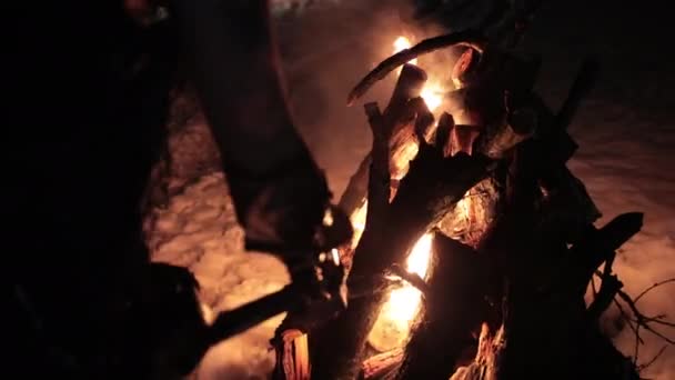 Viking with a torch lights bonfire. Brutal male warrior of dangerous appearance by the fire. — Stock Video