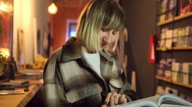 Kütüphanede kitap okuyan bir kadın. Portre okuyan bayan sayfaları çeviriyor. Kadın kitabı.