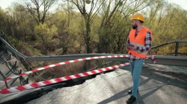 Turuncu yelek giyen bir mühendis ve inşaat kontrol kaskı yönetiyor.