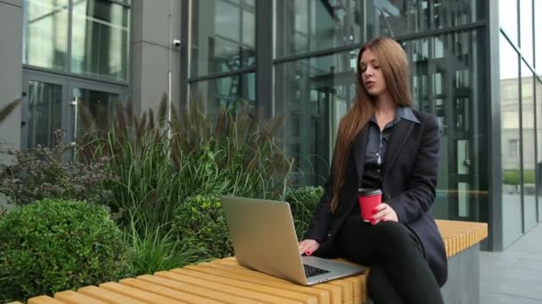 Frau denkt über ein Thema nach. Attraktive braune Haare mit Laptop im Freien. — Stockvideo