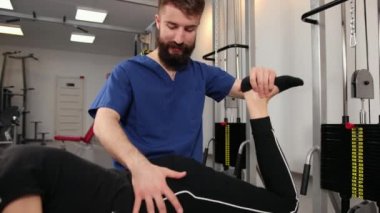 Fizyoterapist hasta çalıştırıyor, bacak esnetme üzerinde çalışıyor. Fizo