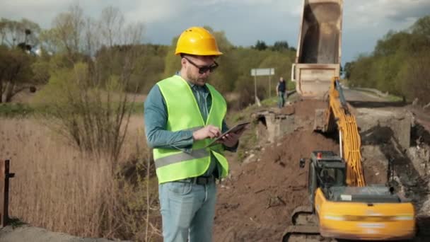 Brug constructie. Road engineer in veiligheidsuniform, een jonge bebaarde ingenieur — Stockvideo