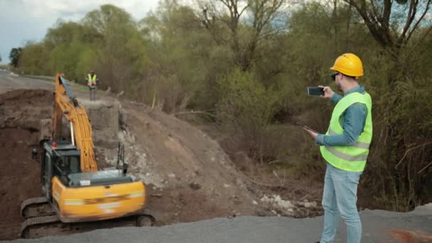 Construcción del puente. Ingeniero de carretera en uniforme de seguridad, un joven ingeniero barbudo — Vídeos de Stock