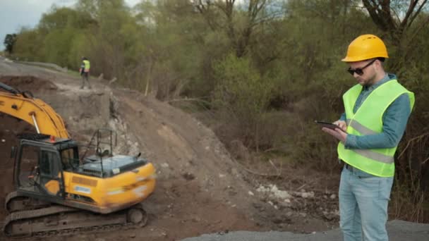 Construcción del puente. Ingeniero de carretera en uniforme de seguridad, un joven ingeniero barbudo — Vídeo de stock