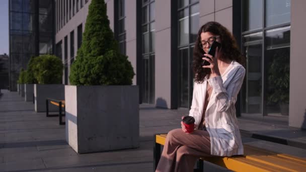 Jonge charmante vrouw bellen met mobiele telefoon tijdens het zitten op een bank — Stockvideo