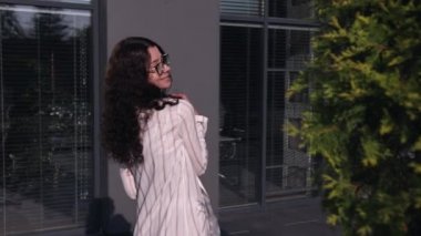 Gün batımında şehirde yürüyen gözlüklü genç bir kadın. Beyaz elbiseli kadın..