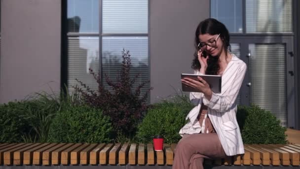 Mujer joven usando tableta digital afuera, usando tableta digital, bebiendo café — Vídeos de Stock