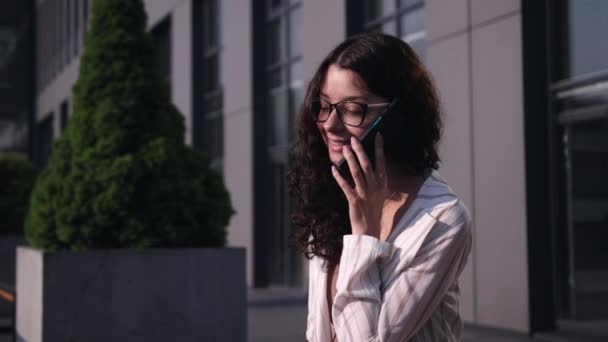 Jovem mulher encantadora chamando com telefone celular enquanto sentado em um banco — Vídeo de Stock