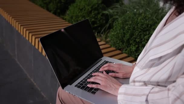 Laptop computer on womens laps outdoor. View from back of woman in white shirt — ストック動画