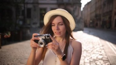 Turist eski şehri keşfediyor. Gülümsüyor, retro kamerada fotoğraf çekiyor. Açık hava.