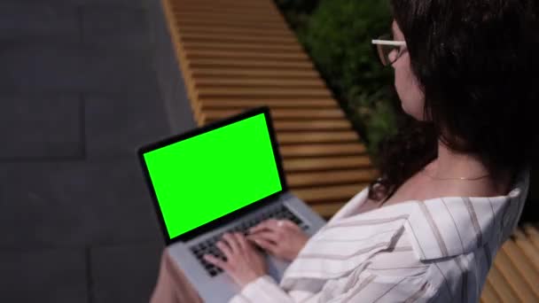 Tylny widok kobieta freelancer pracy na zewnątrz, przy użyciu laptopa zielony ekran — Wideo stockowe
