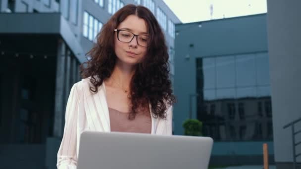 Mulher sorridente em óculos trabalhando com computador remoto ao ar livre, empregado — Vídeo de Stock