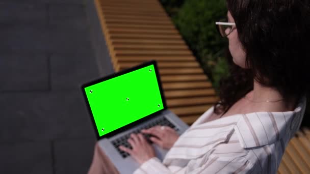 Комп'ютер ноутбуків на жіночих кільцях на відкритому повітрі. Вид ззаду жінки в білому — стокове відео