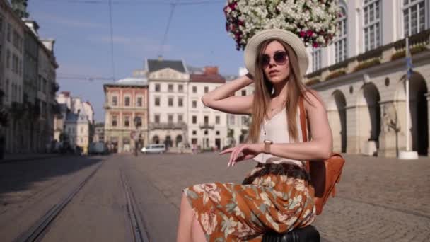 Wanita muda cantik duduk di atas tas perjalanan. Wanita cantik duduk koper — Stok Video
