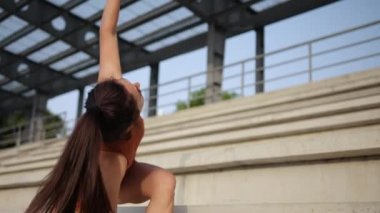Spor ayakkabılı ve eşofmanlı atletik bayan mekik çekiyor. Esniyorum.