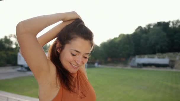 若い魅力的な女性は屋外ワークアウトの前に肩を伸ばしています. — ストック動画